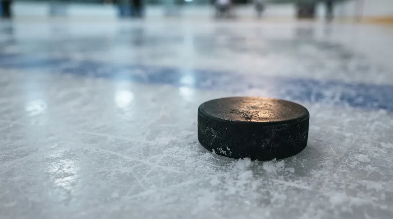 Ein Eishockeypuck liegt auf einer Eisfläche mit Kratzspuren, Nahaufnahme mit kühlen Reflexen