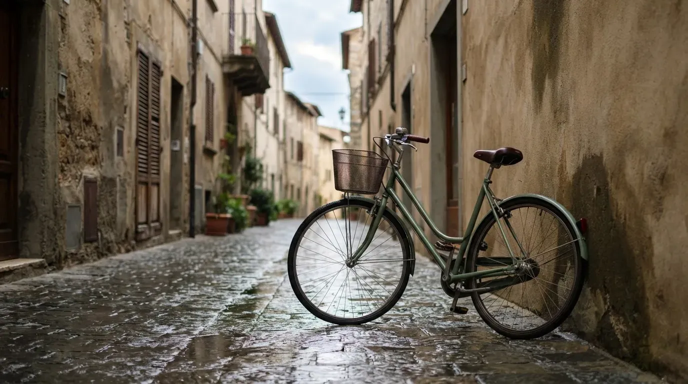 Ein Fahrrad lehnt an einer Mauer in einer Altstadtgasse, das Kopfsteinpflaster glänzt nass nach dem Regen.