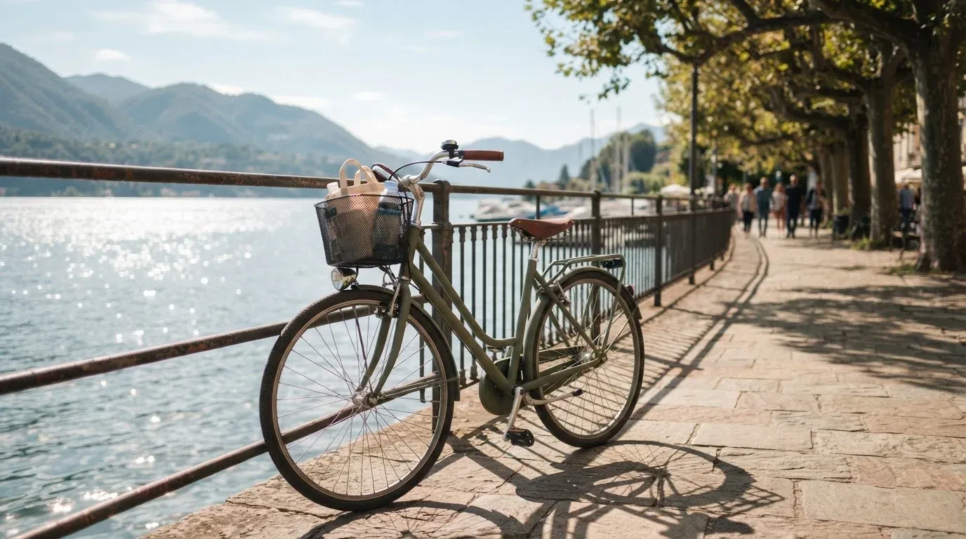 Ein Fahrrad lehnt an einem Geländer einer Uferpromenade an einem See im Sonnenlicht.