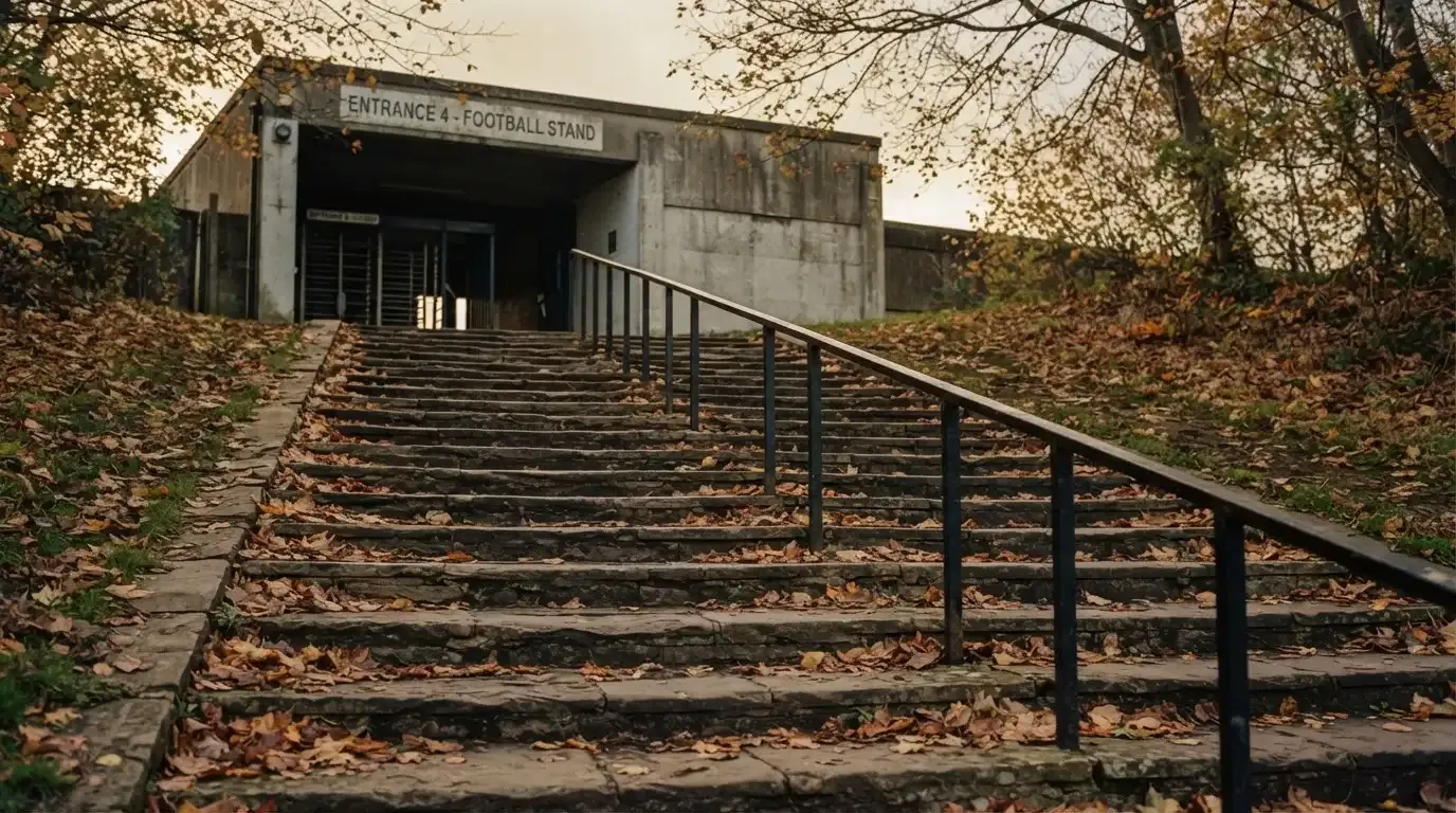 Eine breite Steintreppe führt zum Eingang einer Tribüne, Herbstlaub liegt auf den Stufen.