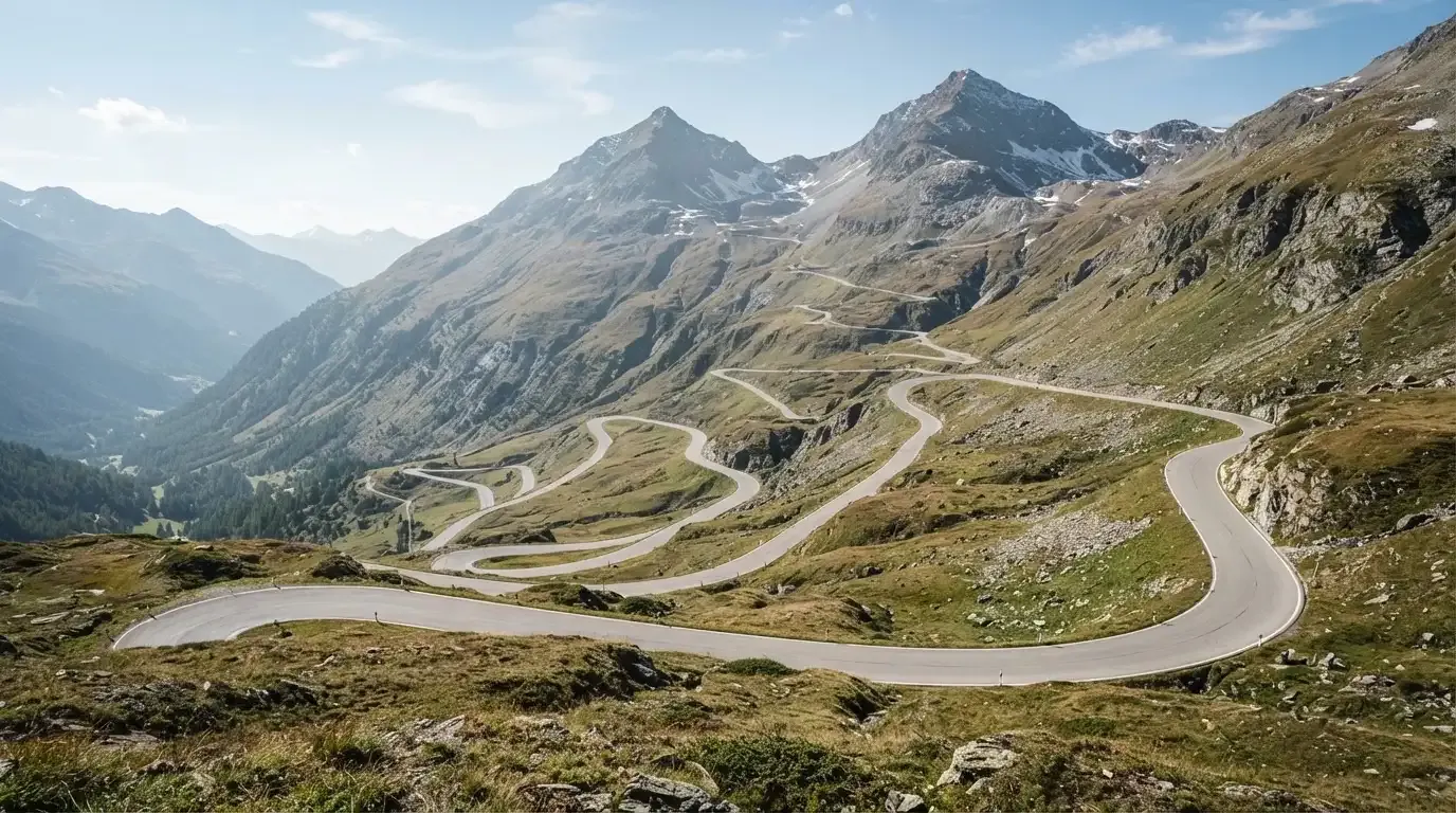 Eine Passstrasse zieht sich in Kehren einen Alpenhang hinauf, kein Fahrzeug ist zu sehen.