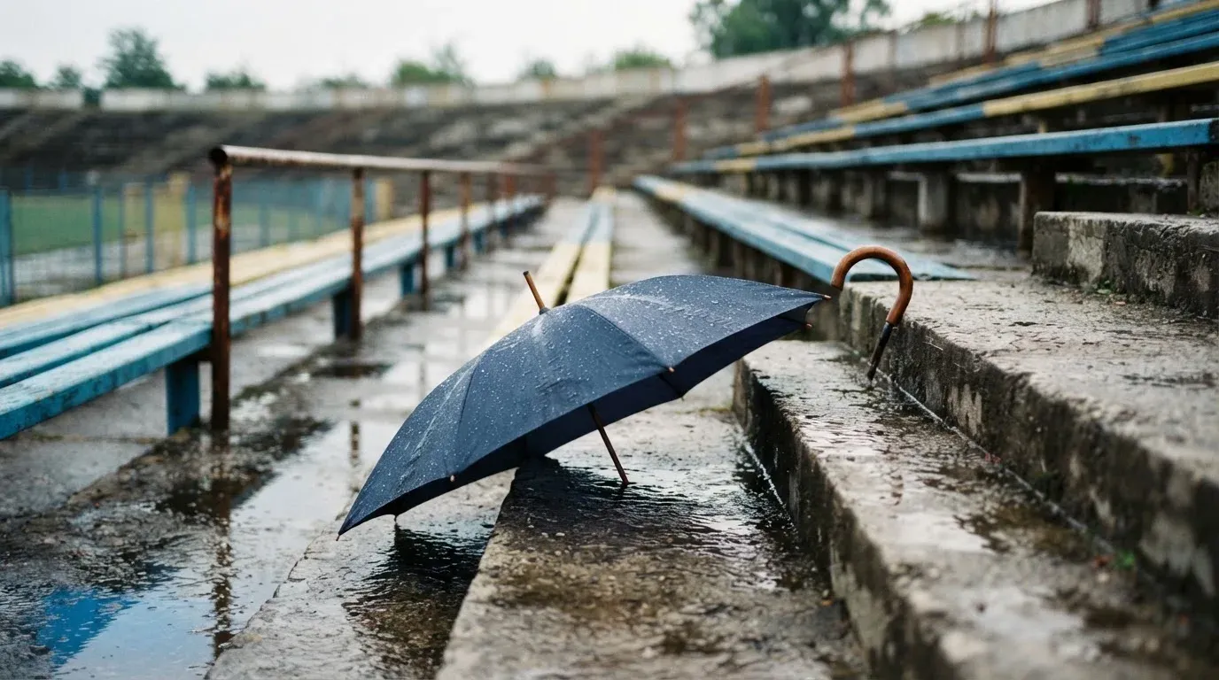 Ein Regenschirm liegt auf einer nassen Treppe zwischen leeren Zuschauerrängen.